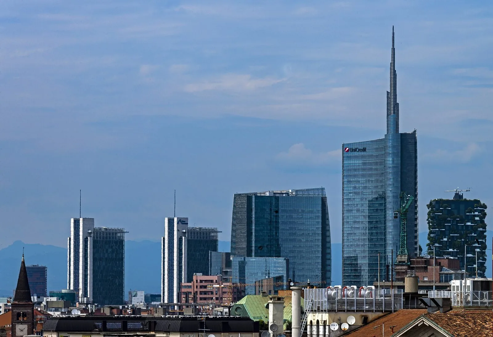 Lo skyline di Milano con la Torre UniCredit e il Bosco Verticale visti oltre i tetti bassi dell'Isola